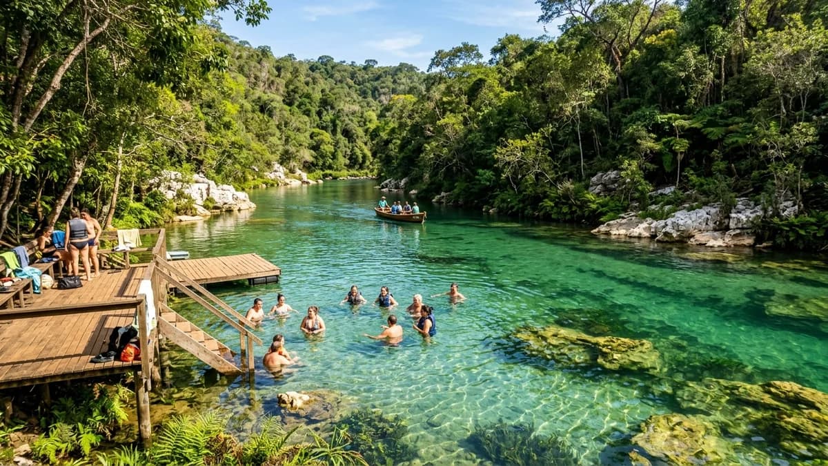 Vista panorâmica de banhistas nadando nas águas cristalinas do Balneário do Rio Betione na Serra da Bodoquena MS com barco elétrico ao fundo e deques de madeira em agosto