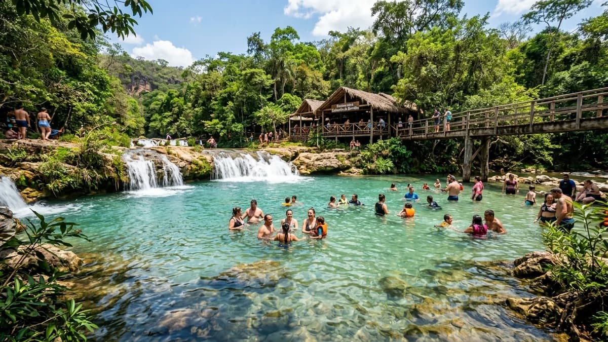 Famílias banhando-se na ampla piscina natural cristalina turquesa da Cachoeira da Barrinha em Bodoquena MS com ponte de madeira e restaurante ao fundo em setembro