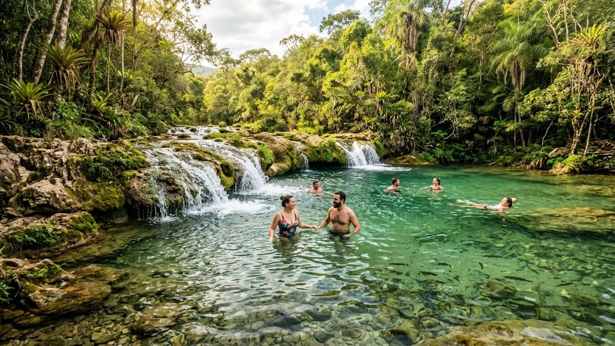 Banhistas relaxando nas águas cristalinas verde-esmeralda do Rio Salobra com cascata e piscinas de tufas calcárias no Eco Serrana Park em Bodoquena MS em agosto